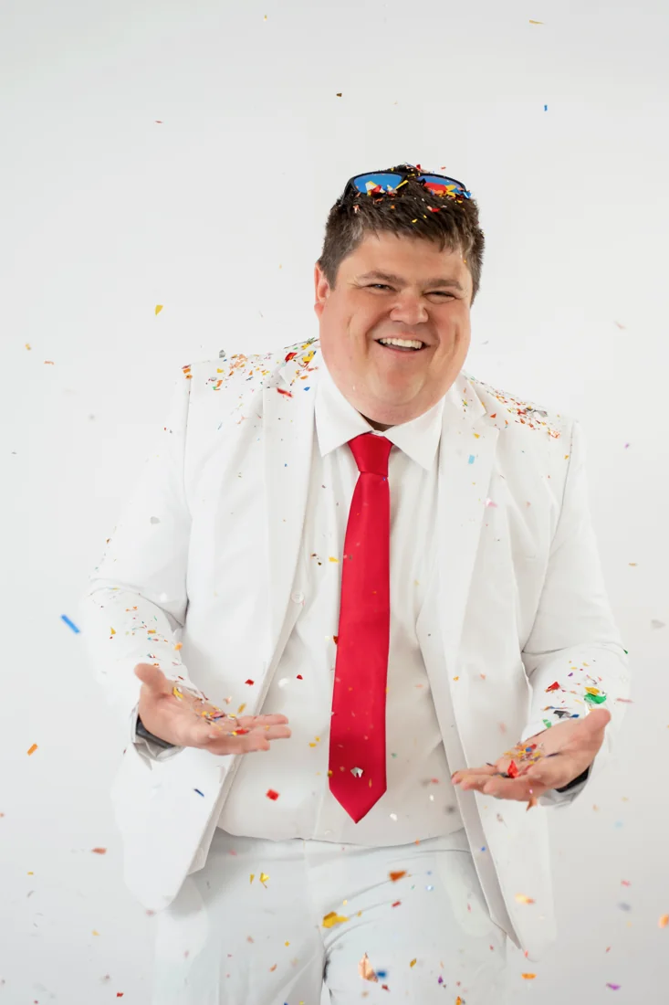 Justin Phillips in a white suit with confetti