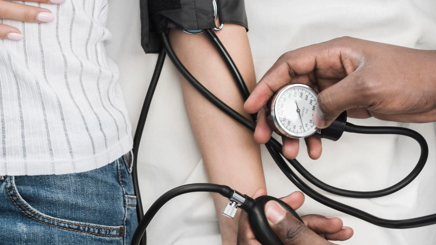 Profesional de la salud midiendo la presión arterial de un paciente con un tensiómetro manual.