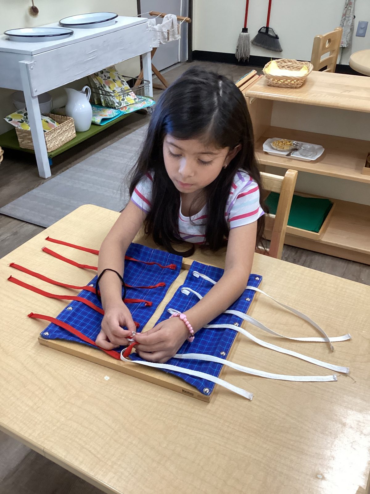 A St. Peter's child practicing buttoning and tying