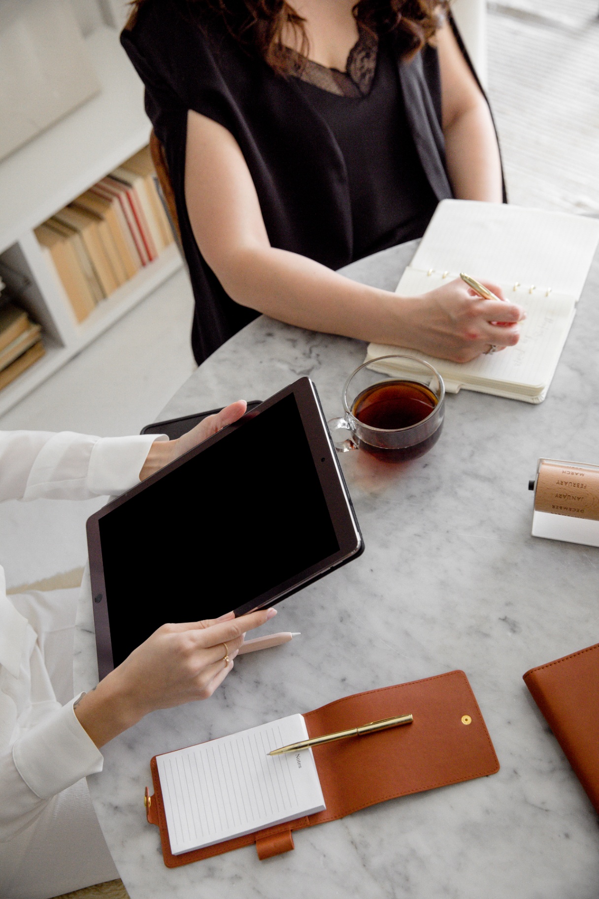 Professional women in a meeting with tablets and reports.
