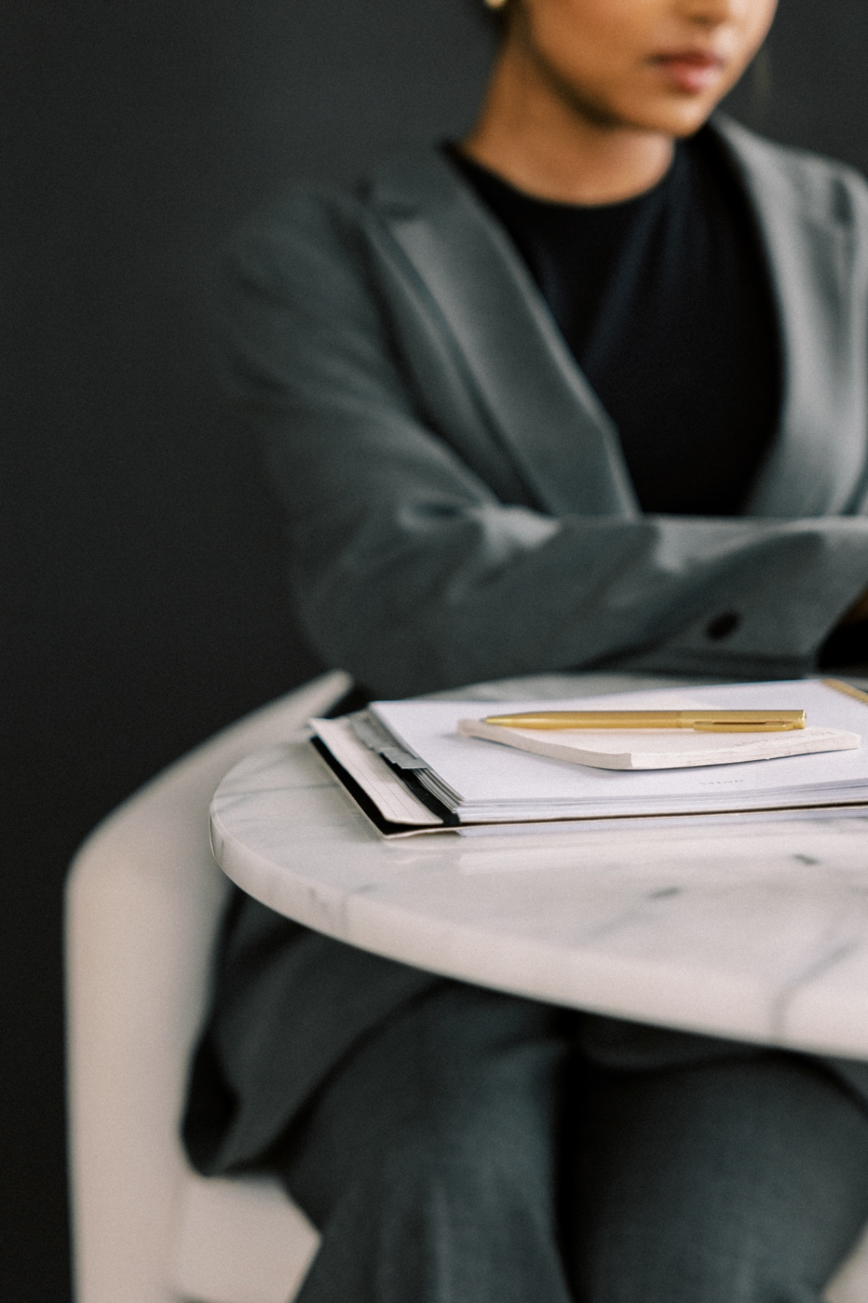 A woman in a grey suit sitting at a table with her planner. A woman in a grey suit sitting at a table with her planner.