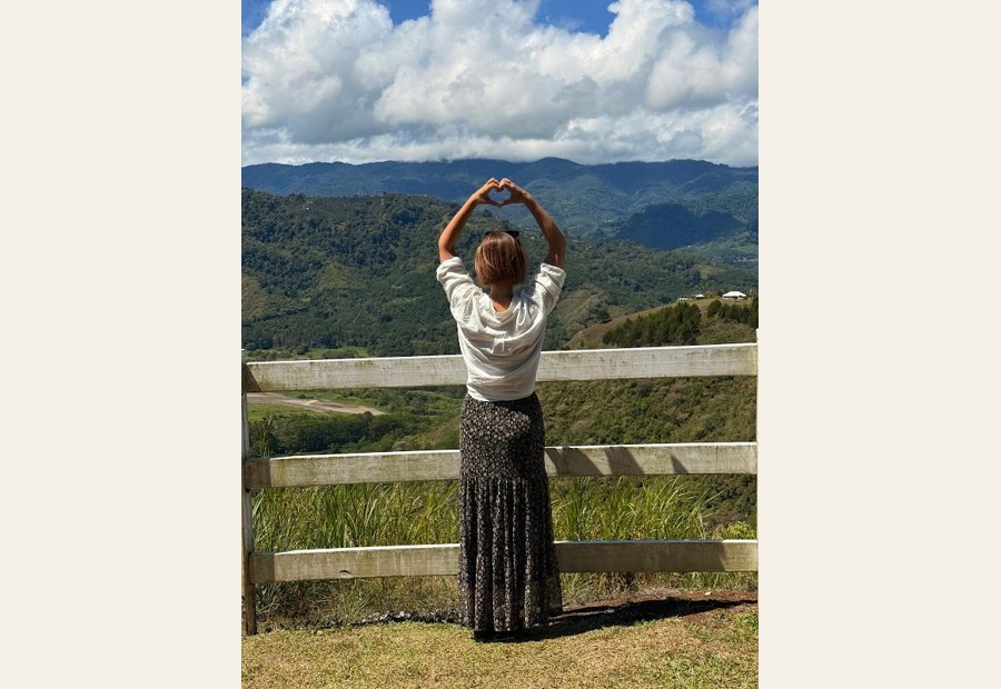 Sarah Carpenter standing at a mountain overlook with arms open