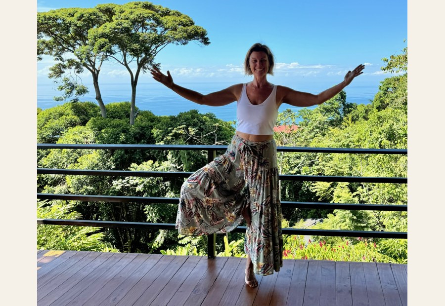 Sarah standing with arms open to a mountain landscape