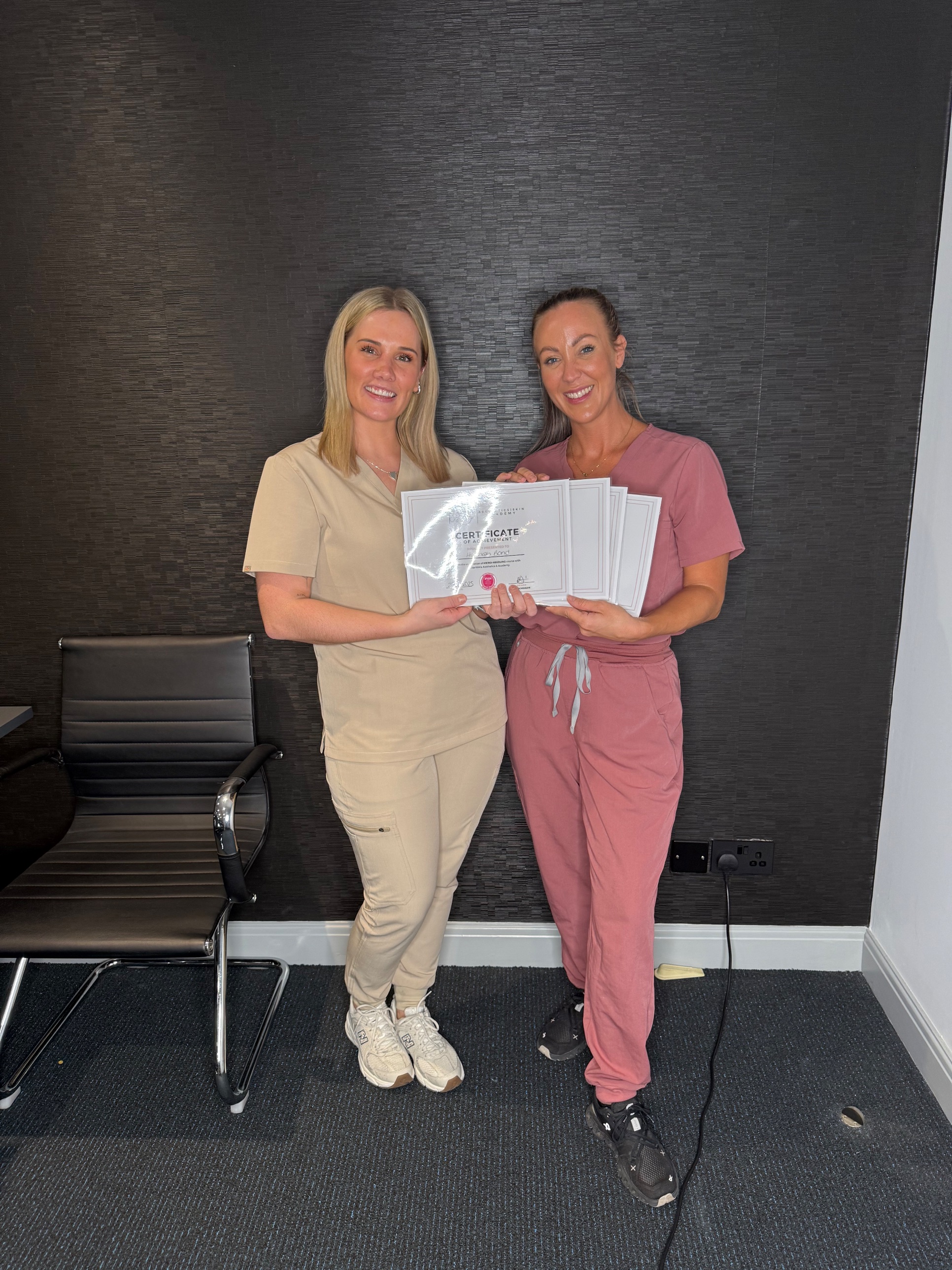 Two students holding their microneedling certificates of achievement