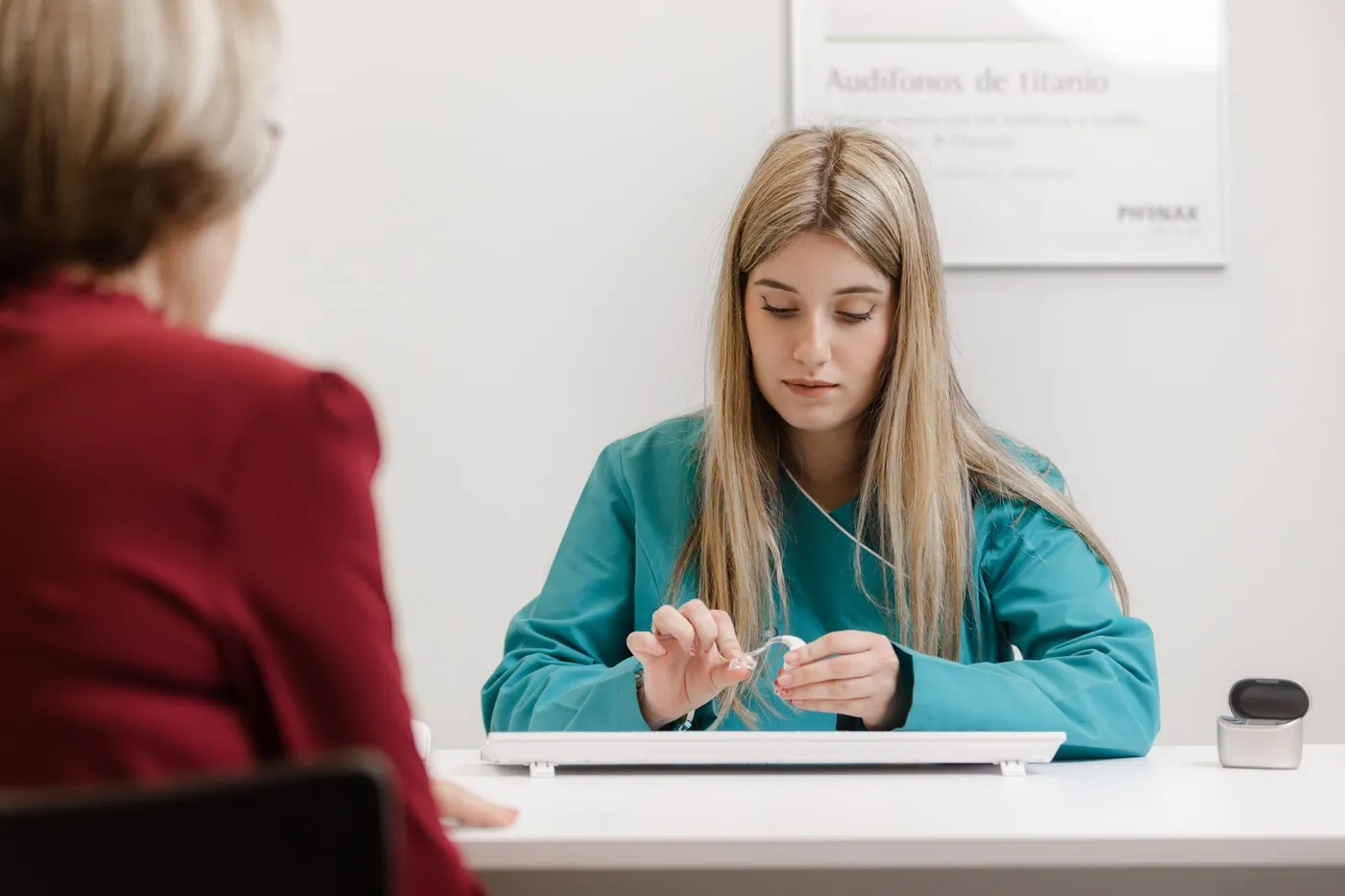 Una audioprotesista de Audioactiva prepara un audífono frente a una paciente en la consulta
