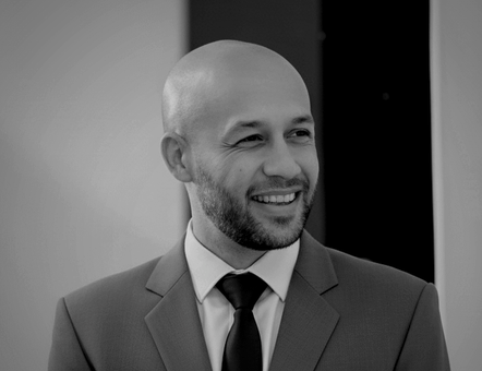 Kris Gilbert smiling, wearing a suit and tie