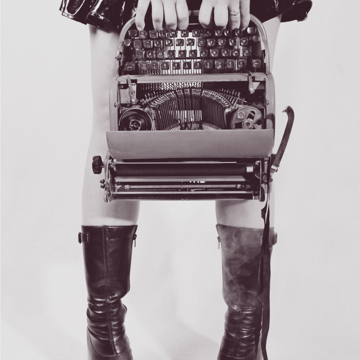 Punk woman holding a typewriter in front of her as if it's a handbag