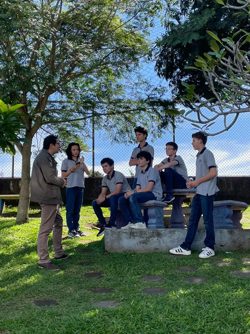 Un grupo de estudiantes conversa con un miembro del personal en los jardines del colegio