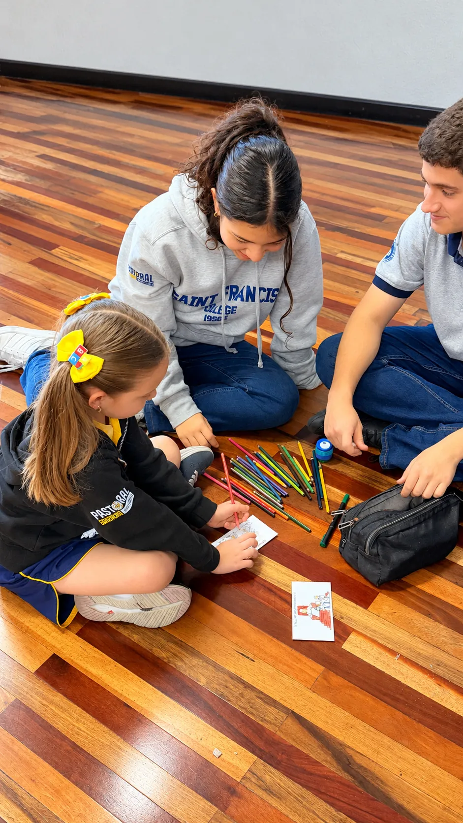 Estudiantes de Secundaria colorean junto a una niña de Primaria en una actividad de Pastoral