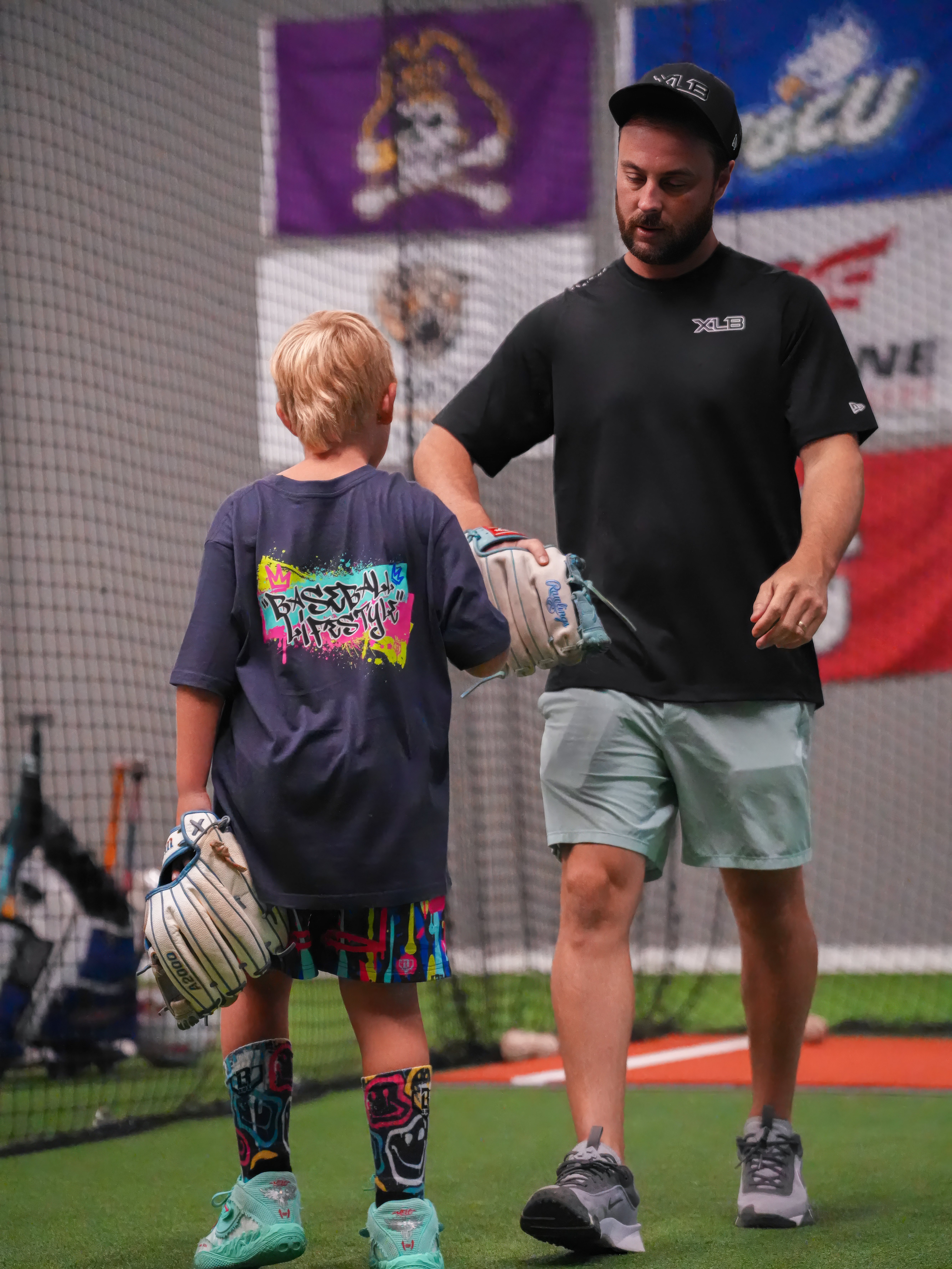 XLB Training coach walking alongside a young baseball player during a development session