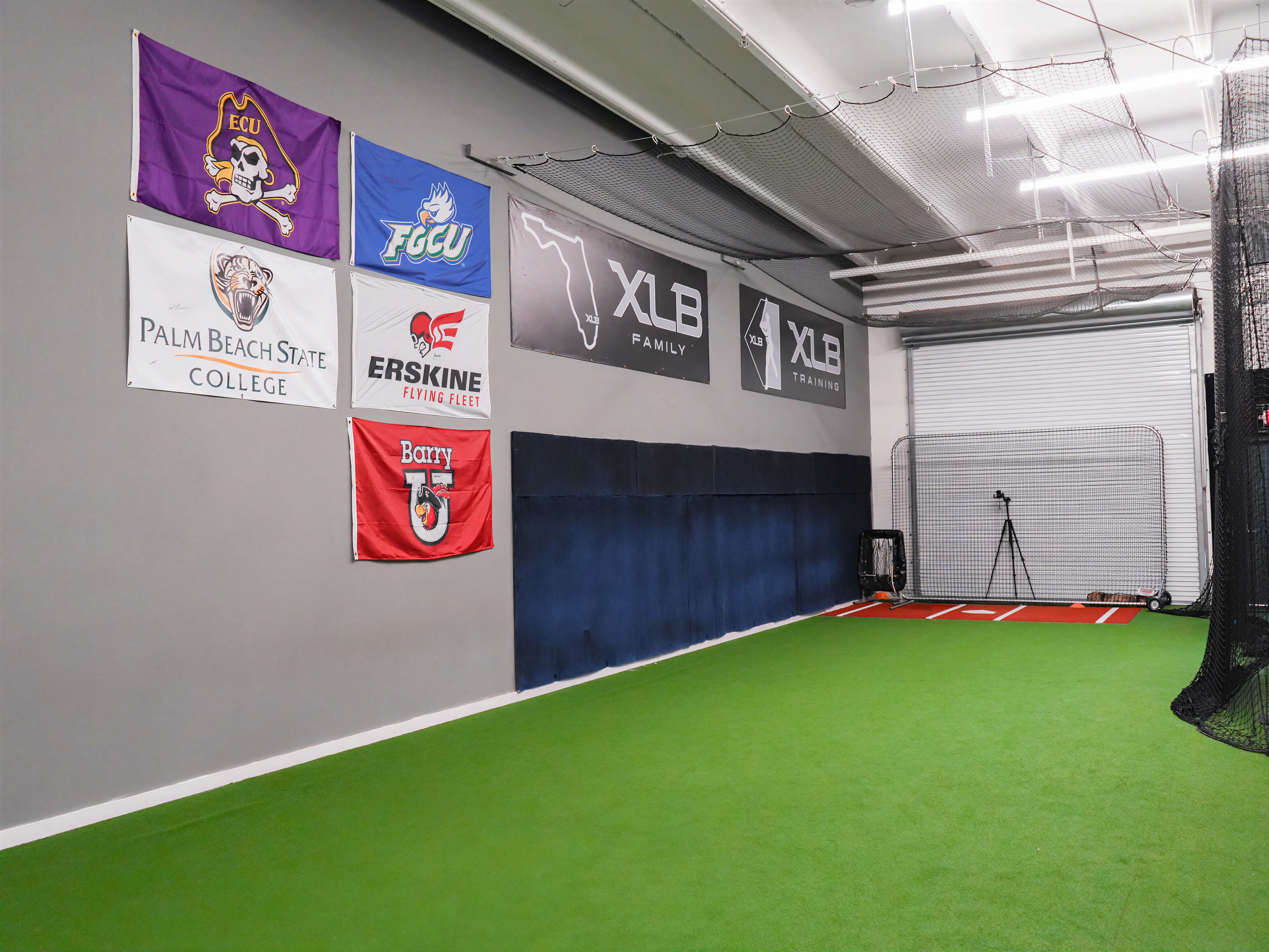 College commitment flag wall at XLB Training displaying programs where XLB players have committed