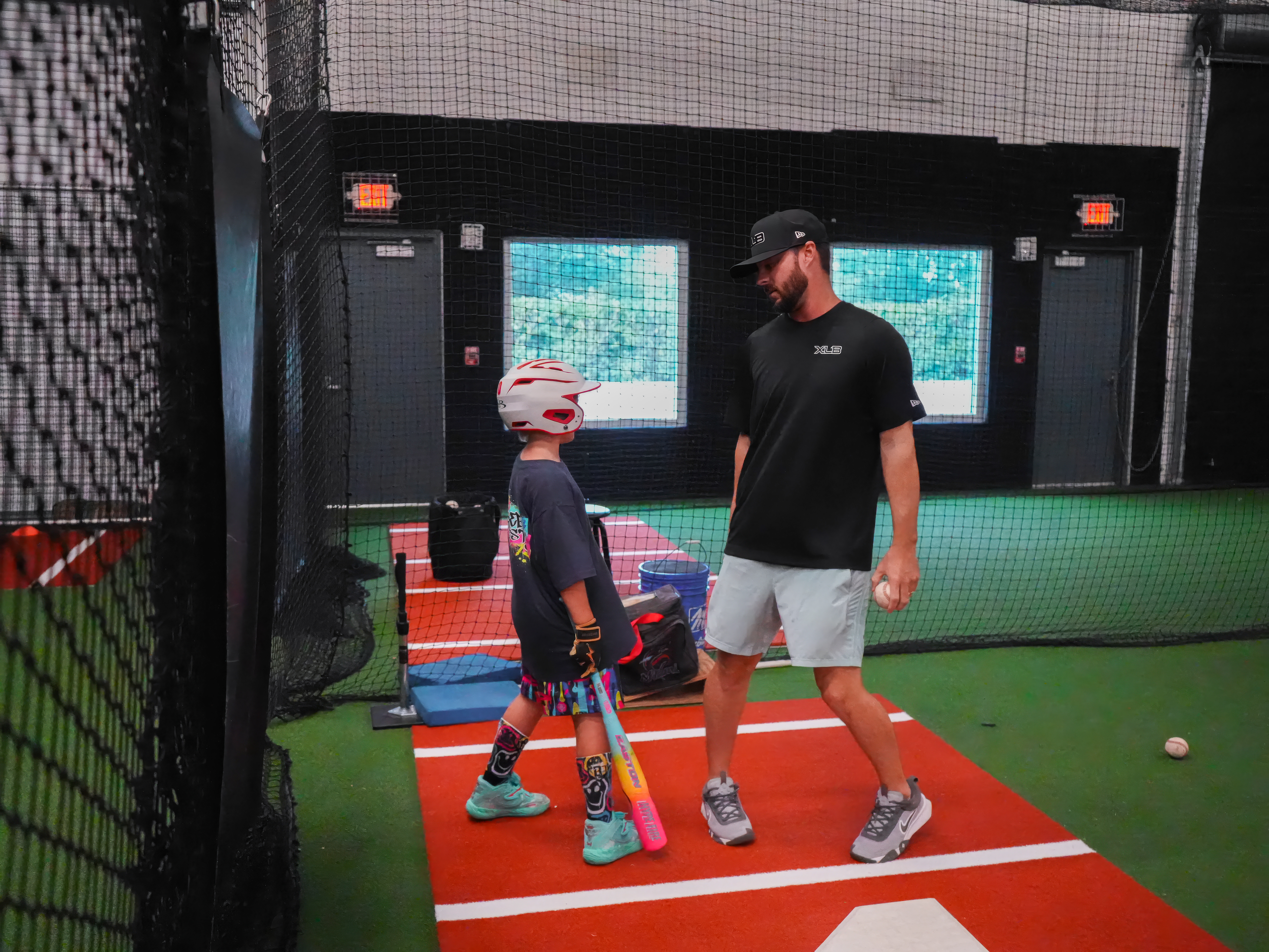 XLB Training coach giving one-on-one hitting instruction to a young player in the cage in Boynton Beach