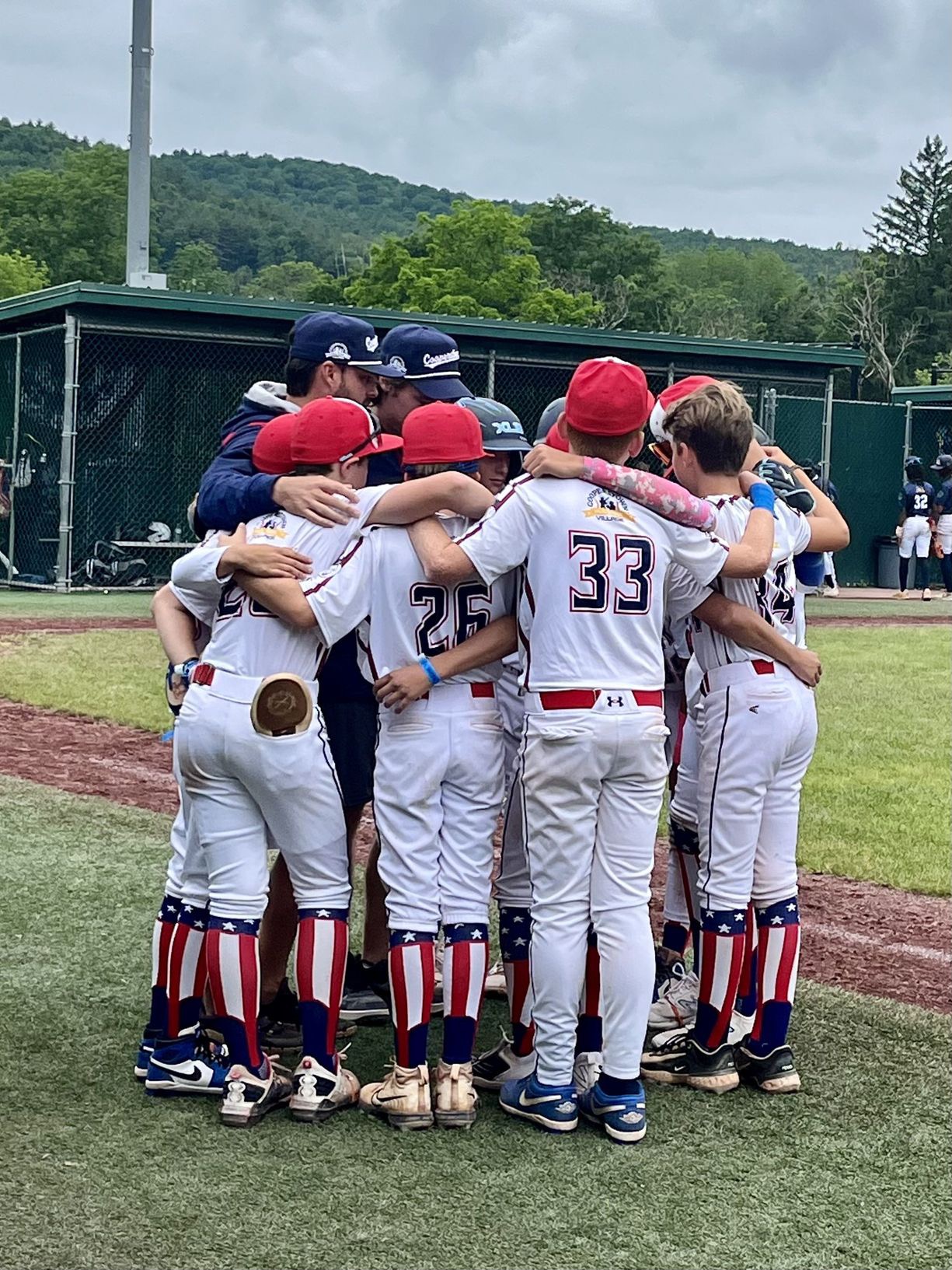 XLB Wave travel baseball team huddled with their coach before a game at Cooperstown