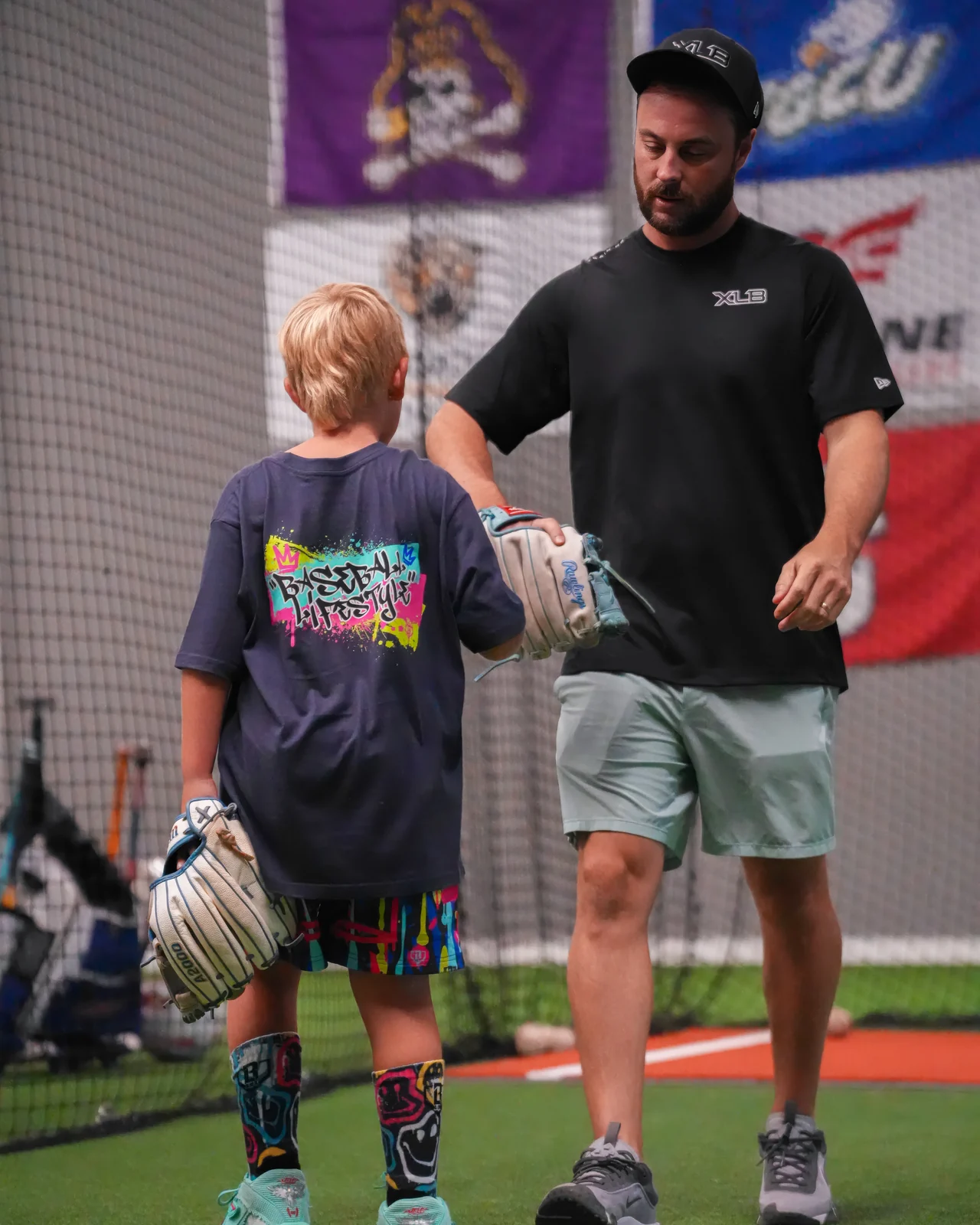 XLB Training coach walking alongside a young baseball player during a development session