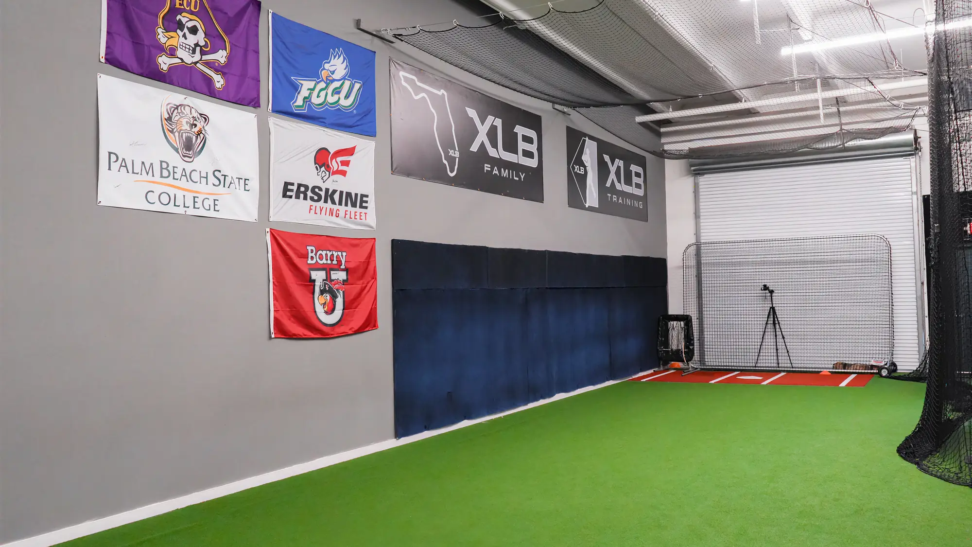 College commitment flag wall at XLB Training displaying programs where XLB players have committed