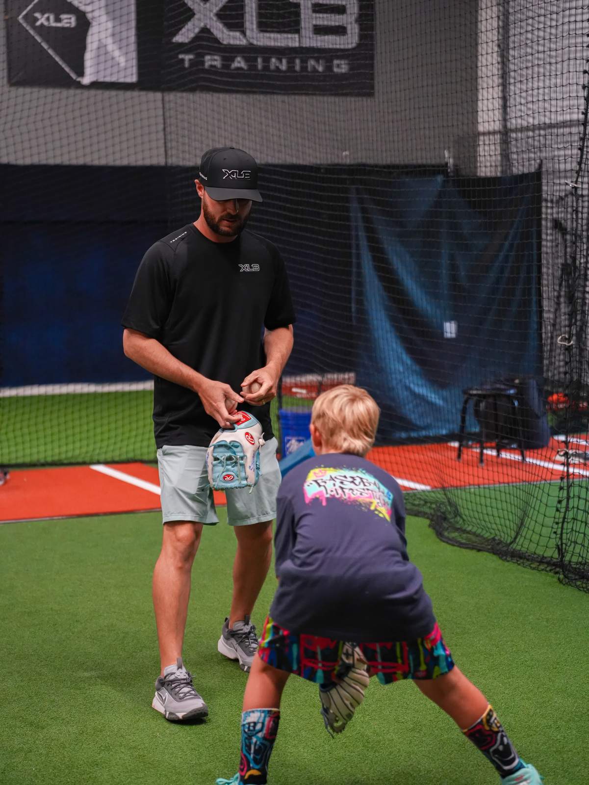 An XLB Training coach teaching a young player a baseball grip during a youth baseball camp in Boynton Beach, Florida