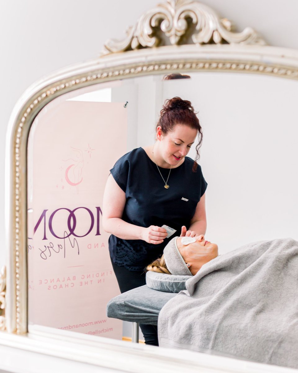 Michelle giving a treatment in her Moon & Mars treatment room, seen in a mirror