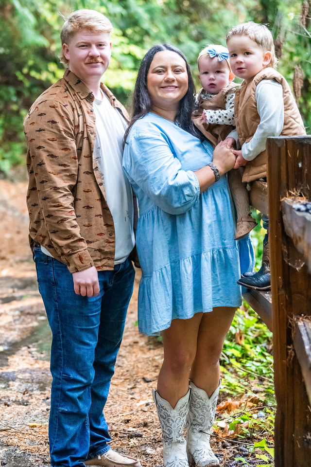 Young family of four by a rustic fence in autumn