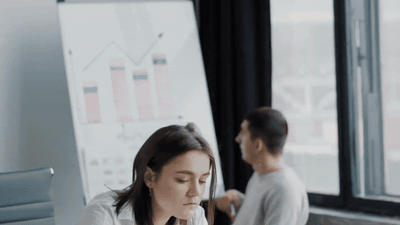 Team member working independently with metrics and accountability charts visible — owning her work without a manager hovering