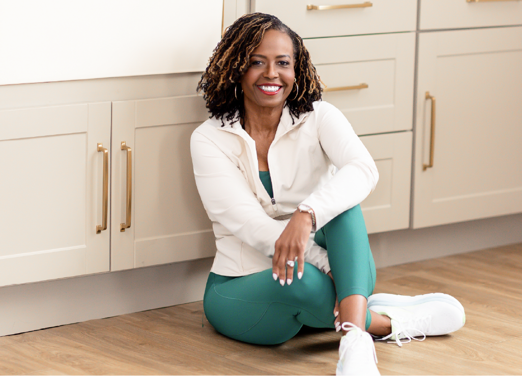 Glynnis Day Thatch, NP, seated in her kitchen wearing activewear.