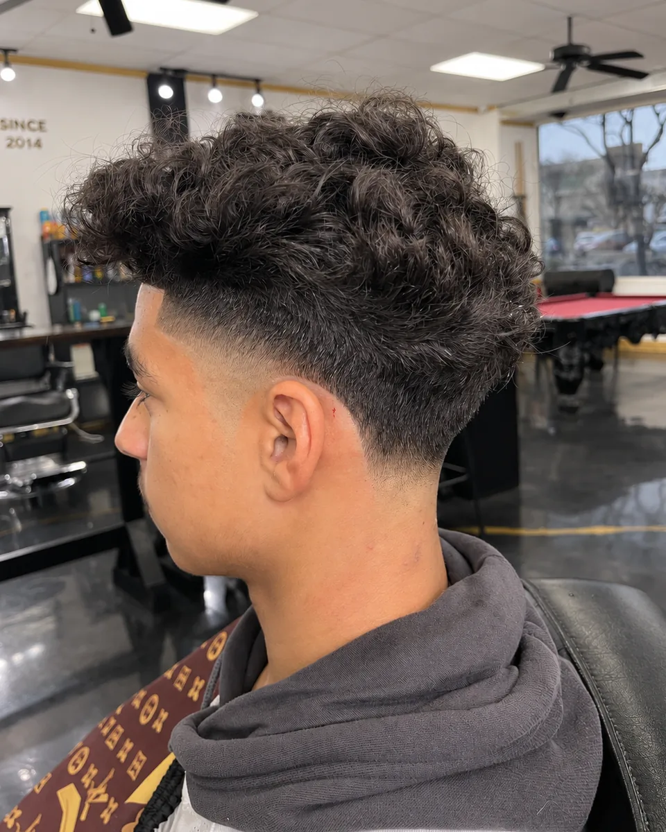 Front view of a styled fade with a sharp center part and textured top