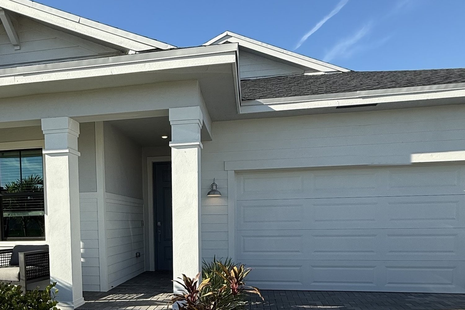 Covered front entry and garage of a new-construction home in Port St. Lucie