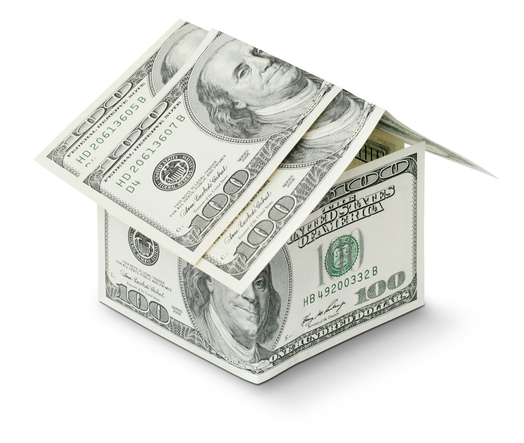 A small, stylized house made of $100 bills. A small, stylized house made of $100 bills.