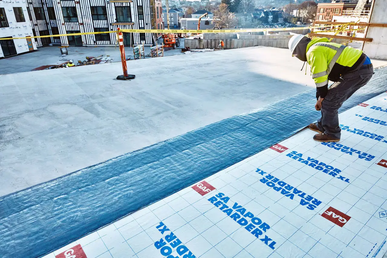 A commercial roofer repairing a roof in a downtown office building.