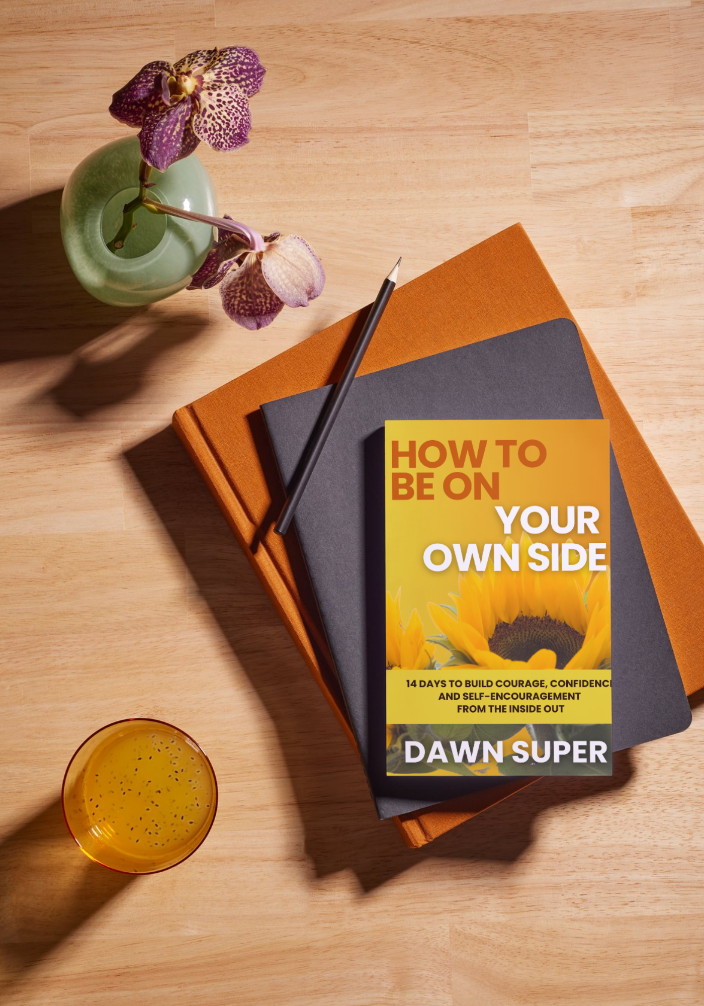 A styled flat-lay photo showing Dawn Super's book "How to Be on Your Own Side: 14 Days to Build Courage, Confidence, and Self-Encouragement from the Inside Out" resting on a stack of orange and dark gray journals on a warm wood surface, accompanied by a pencil, a small green vase with purple orchids, and a glass of golden juice. A styled flat-lay photo showing Dawn Super's book "How to Be on Your Own Side: 14 Days to Build Courage, Confidence, and Self-Encouragement from the Inside Out" resting on a stack of orange and dark gray journals on a warm wood surface, accompanied by a pencil, a small green vase with purple orchids, and a glass of golden juice.