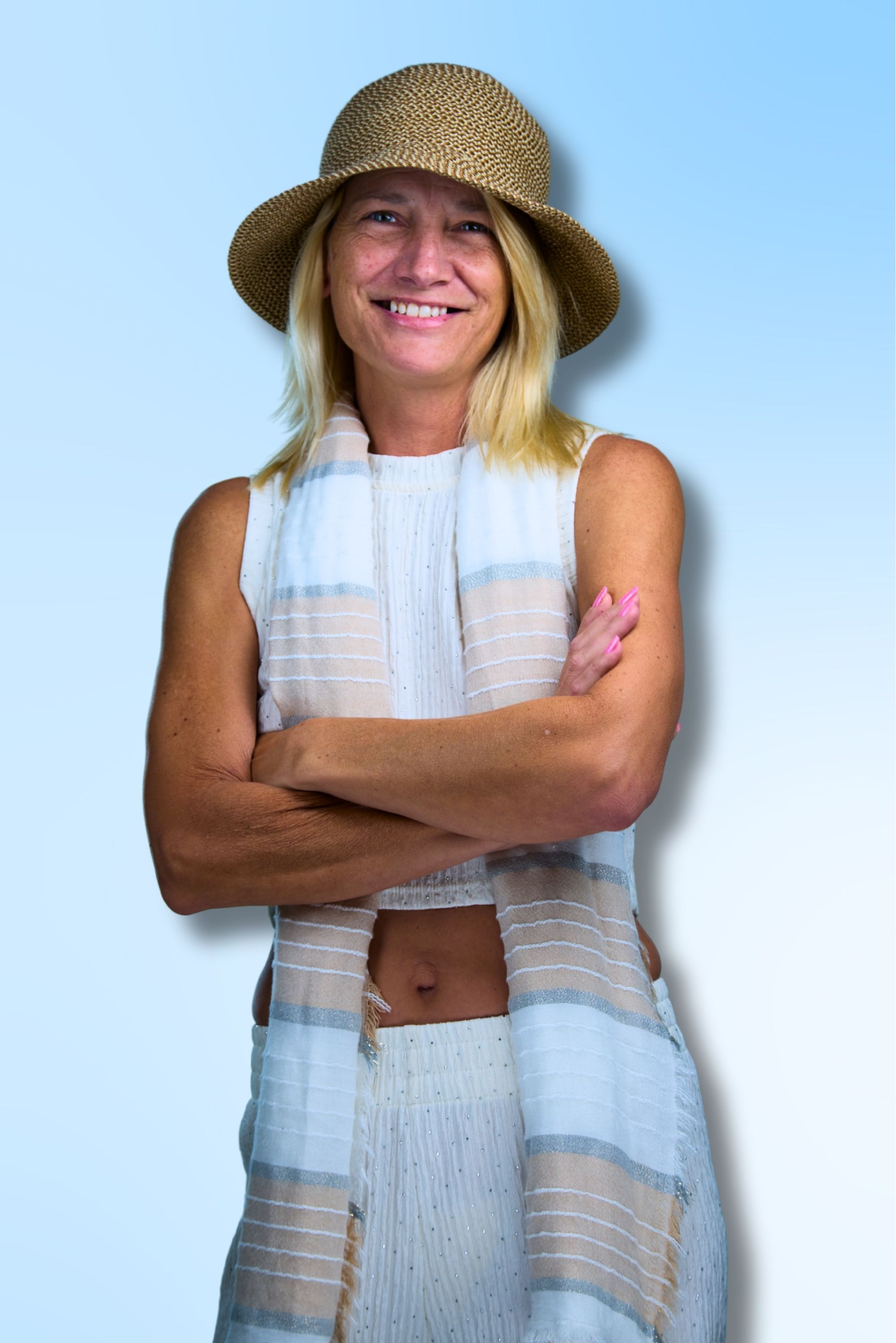 Dawn Super smiling with arms crossed, wearing a hat and light outfit, standing confidently against a soft blue background.