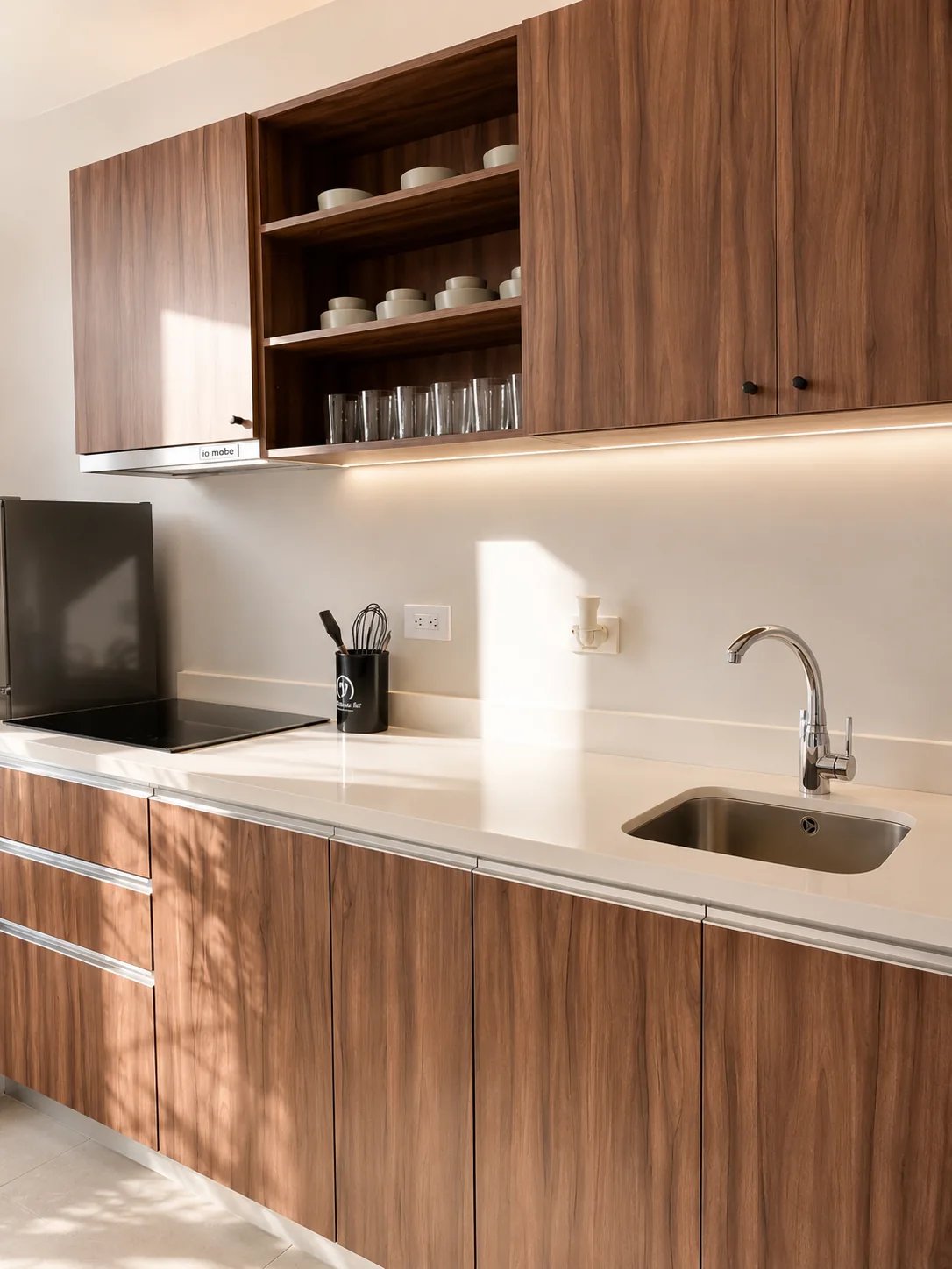 Cocina del departamento muestra de Renéva Playa del Carmen, con alacenas de madera, cubierta de cuarzo e iluminación bajo gabinete