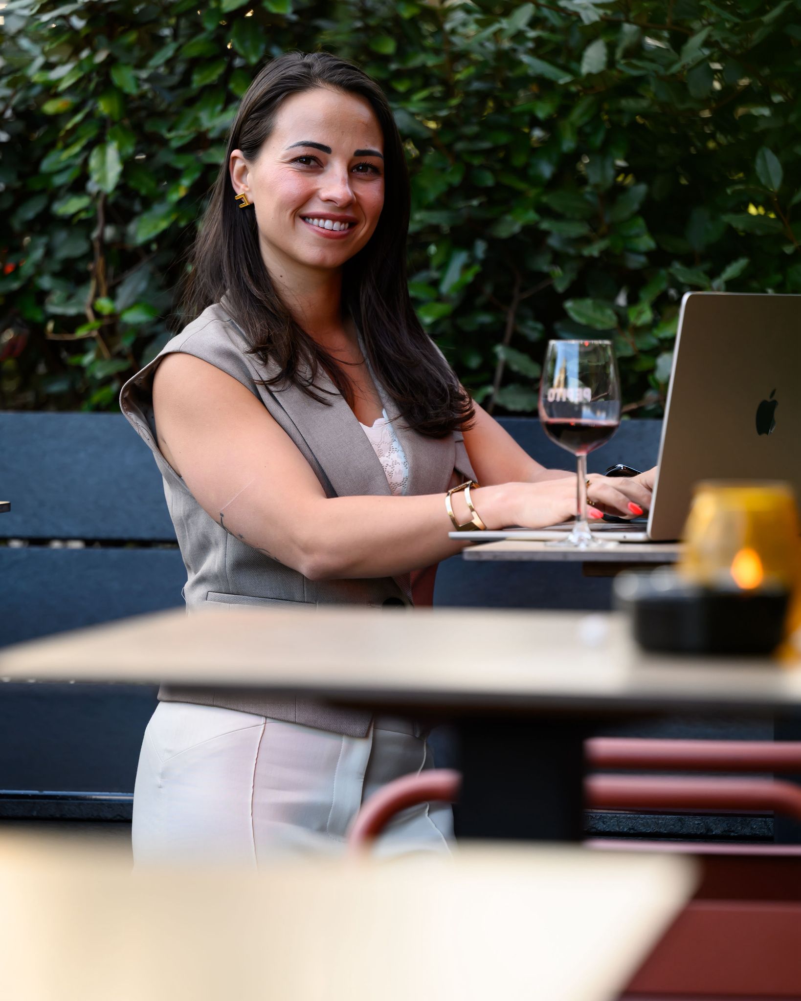 Manon Sciarli werkend op haar laptop op een groen terras