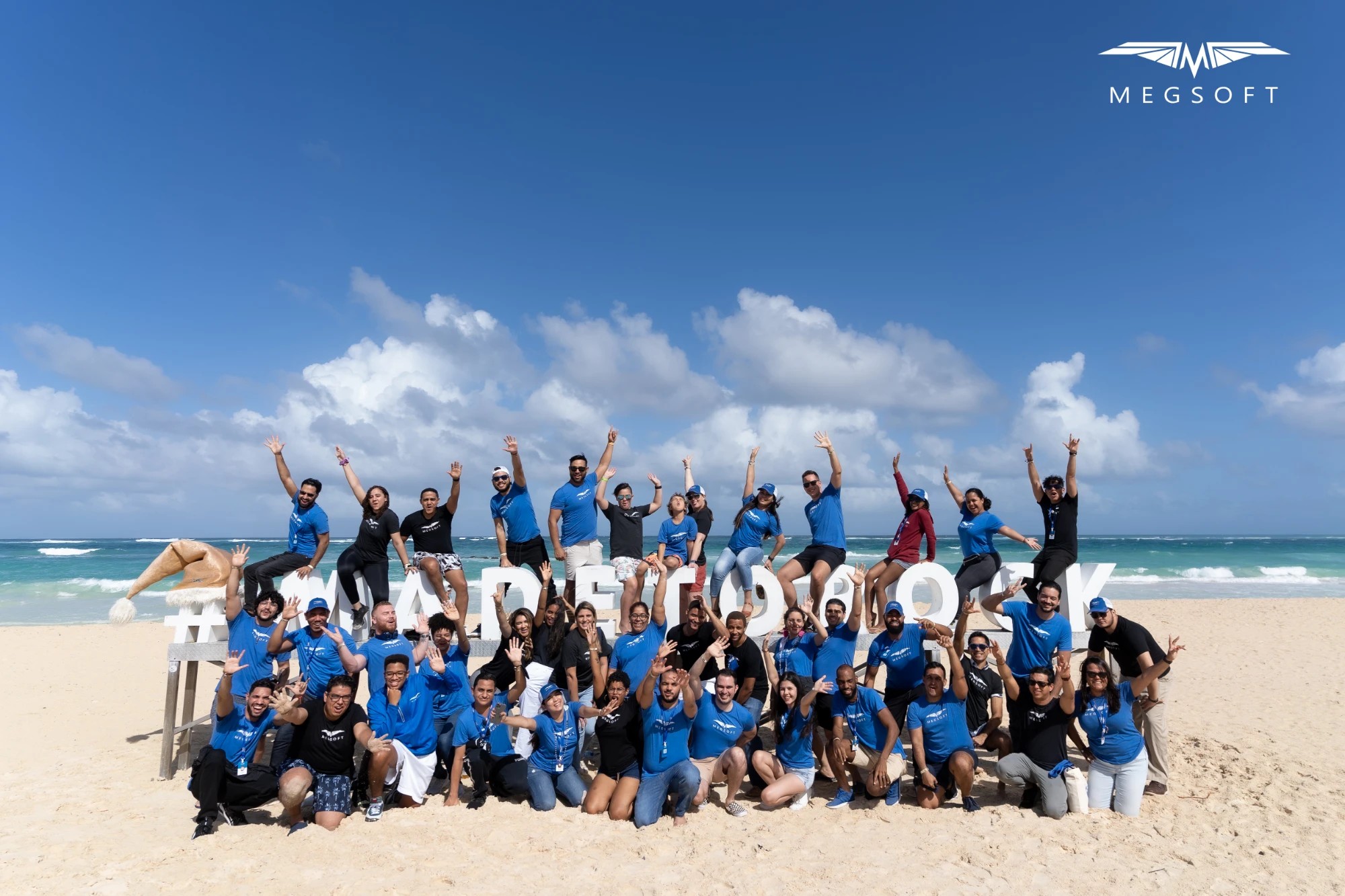 The full Megsoft team at the annual retreat, on the beach behind #MADETOROCK letters