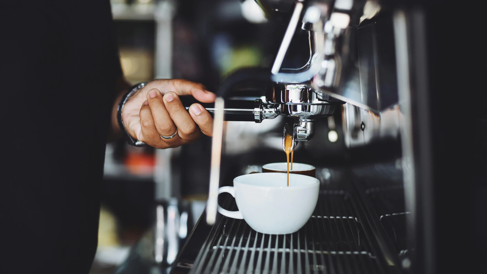 Espresso pouring from a portafilter into a white cup