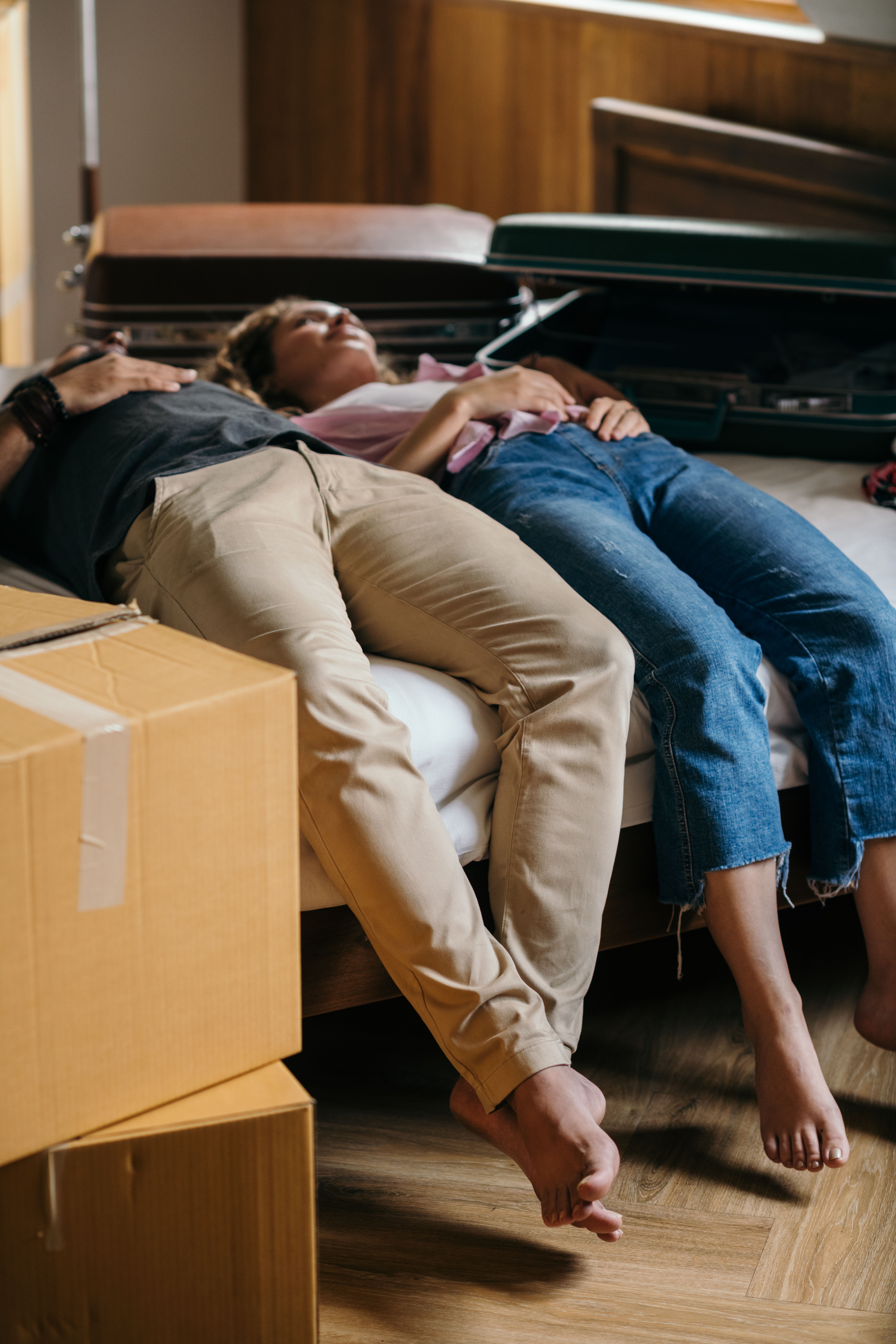 A couple resting together surrounded by moving boxes in their new home