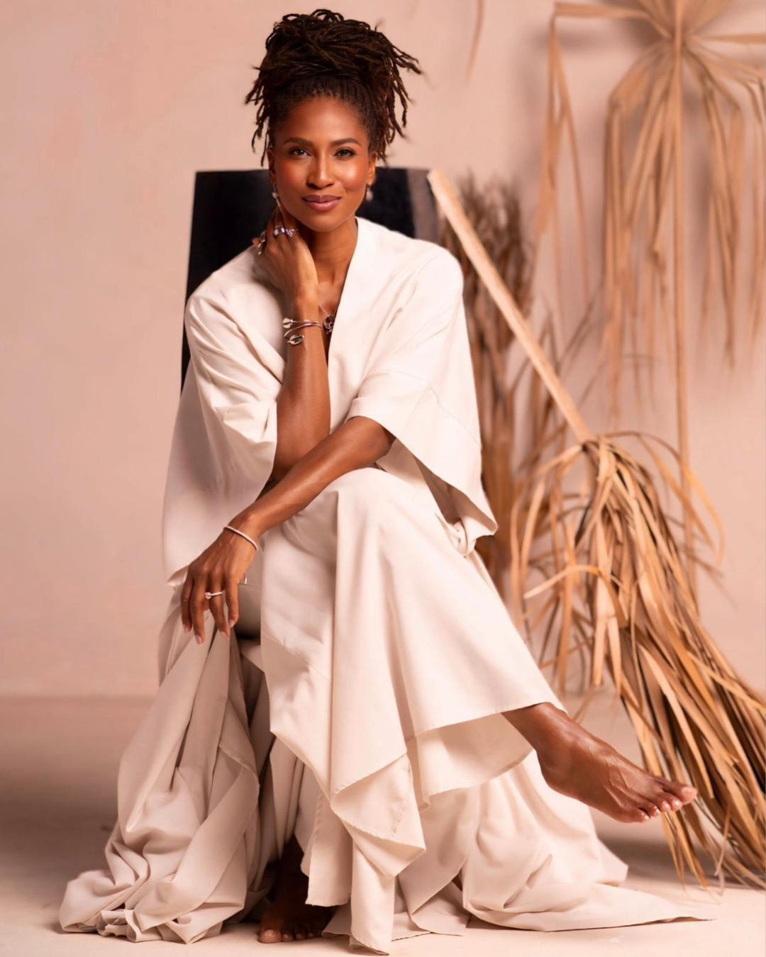 Koya Webb seated in a flowing cream robe