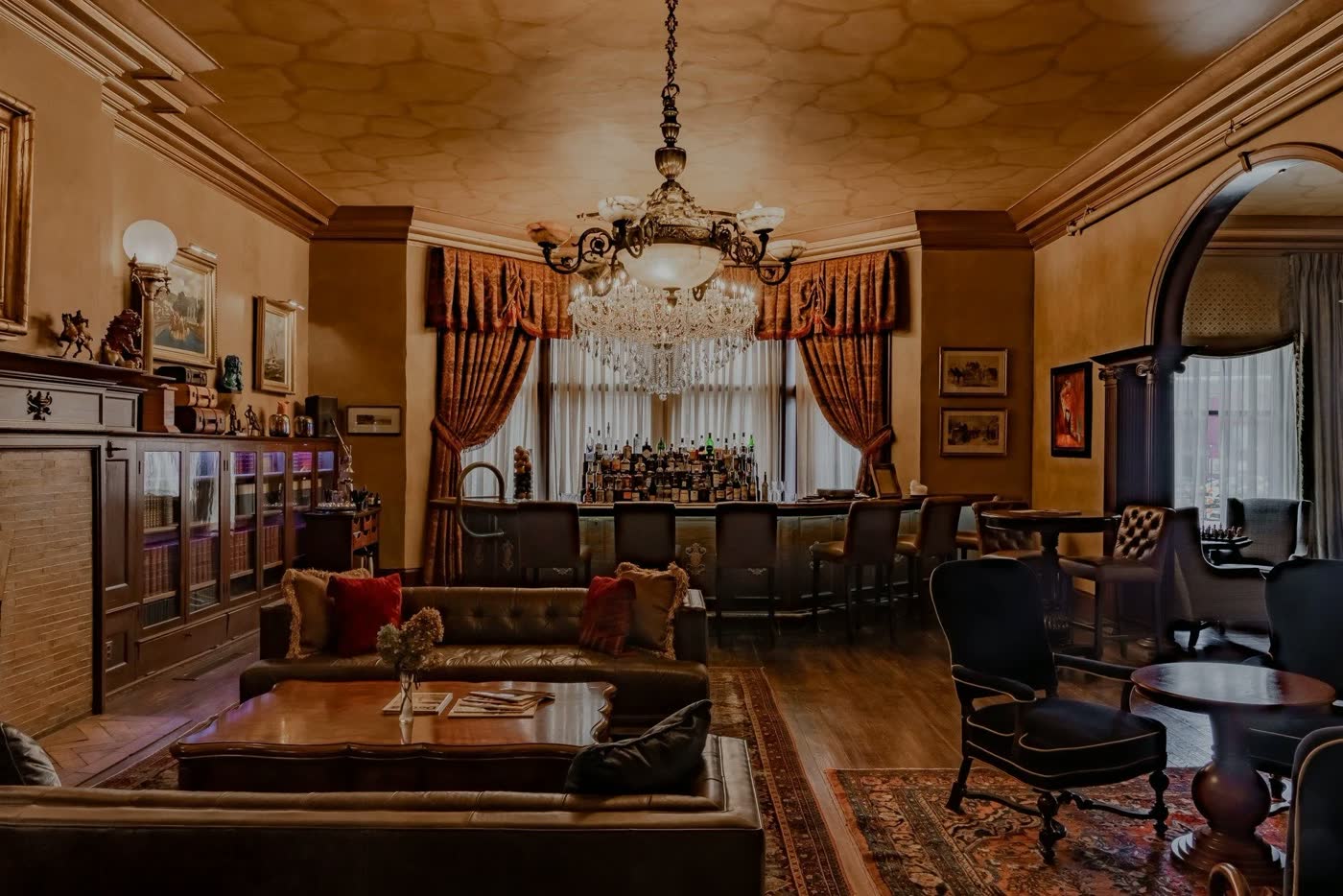 The Library: sofas, patterned rugs and a chandelier in a warm wood-panelled room
