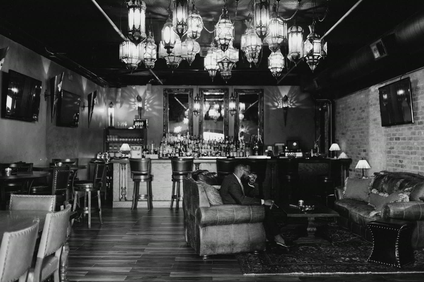 Black-and-white view of the cigar bar with chandeliers and leather seating