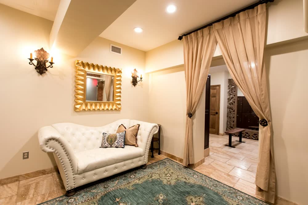 The spa lounge: a tufted ivory sofa beneath a gilded mirror