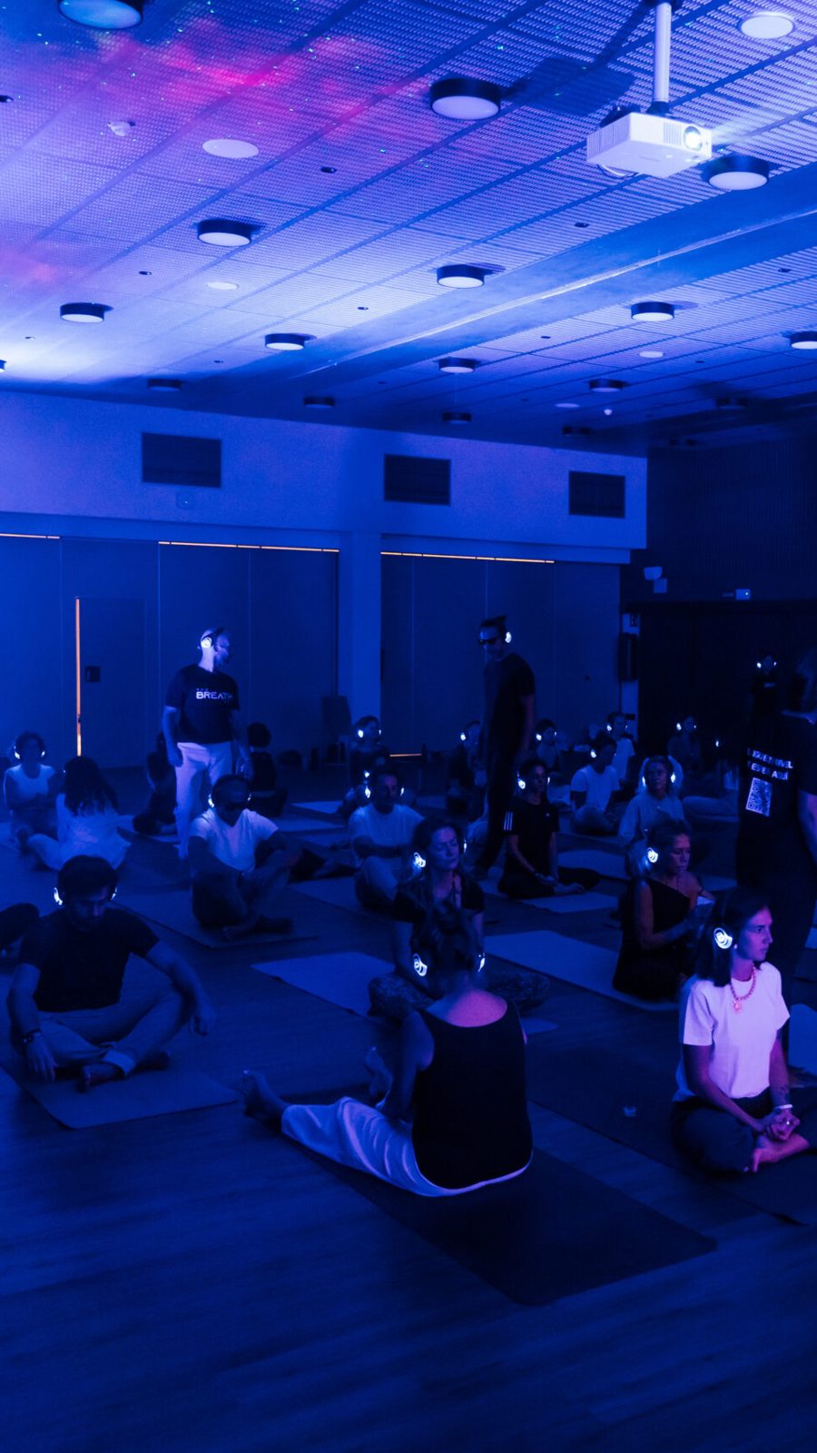 Sala llena en un taller de BREATHE UP, con luces azules y auriculares