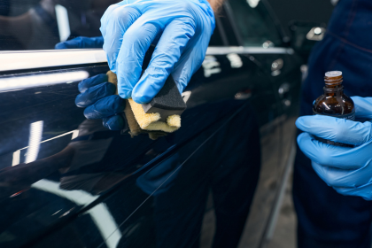 zaro detailing technician applying a ceramic coating to a a dark blue car