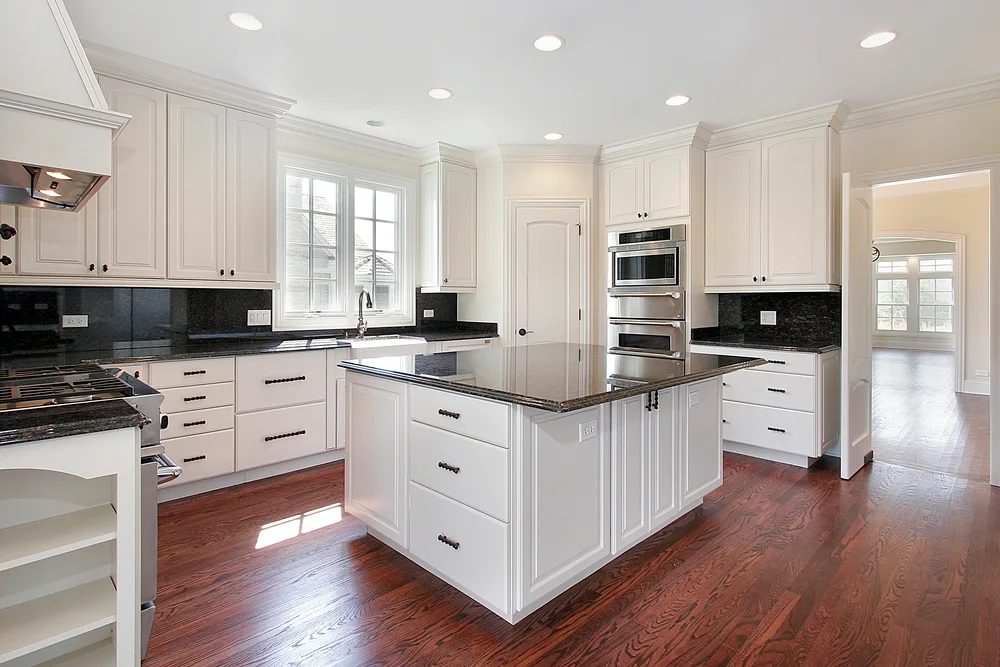 Completed white kitchen remodel with island and dark countertops