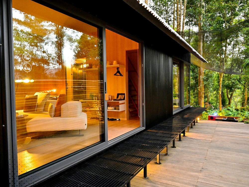 Modern cabin exterior with large glass windows, wood deck, and forest surroundings, ideal for a Gatlinburg TN home inspection.