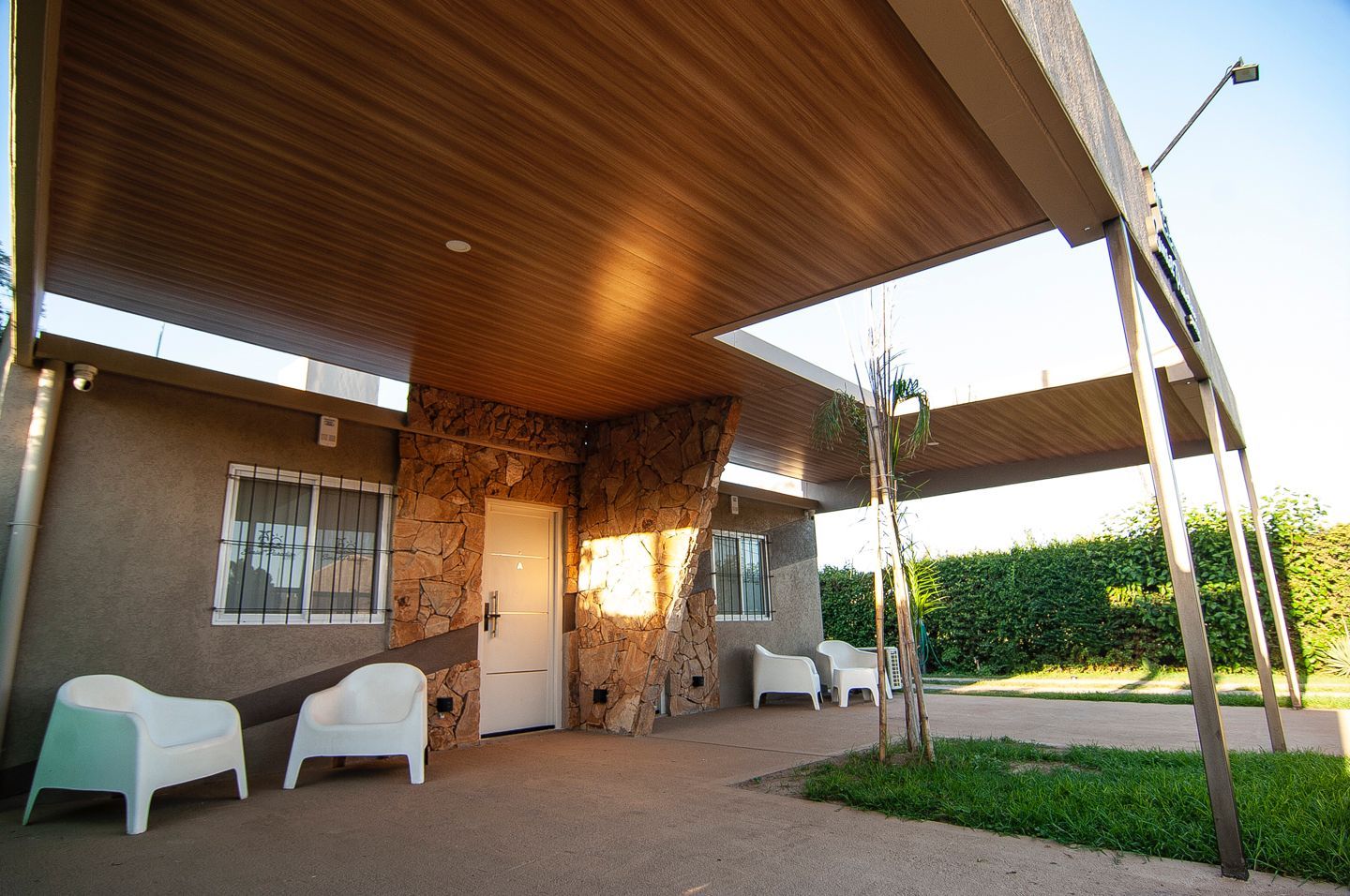 Galería exterior techada con sillones blancos y jardín