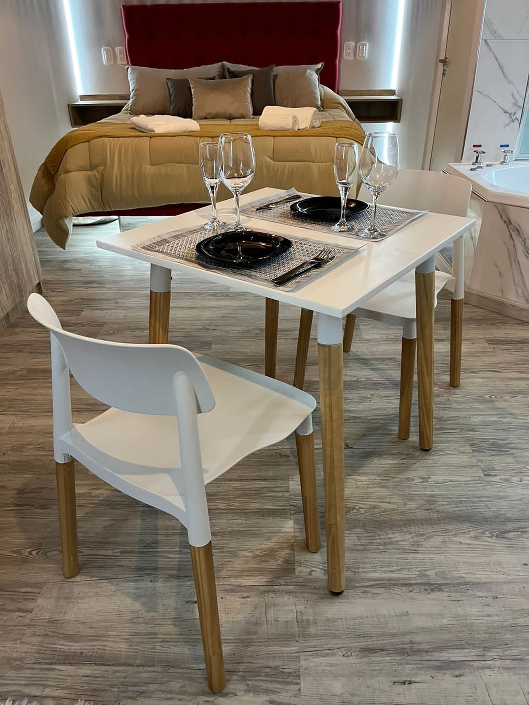 Mesa para dos con copas, lista para brindar frente a la cama