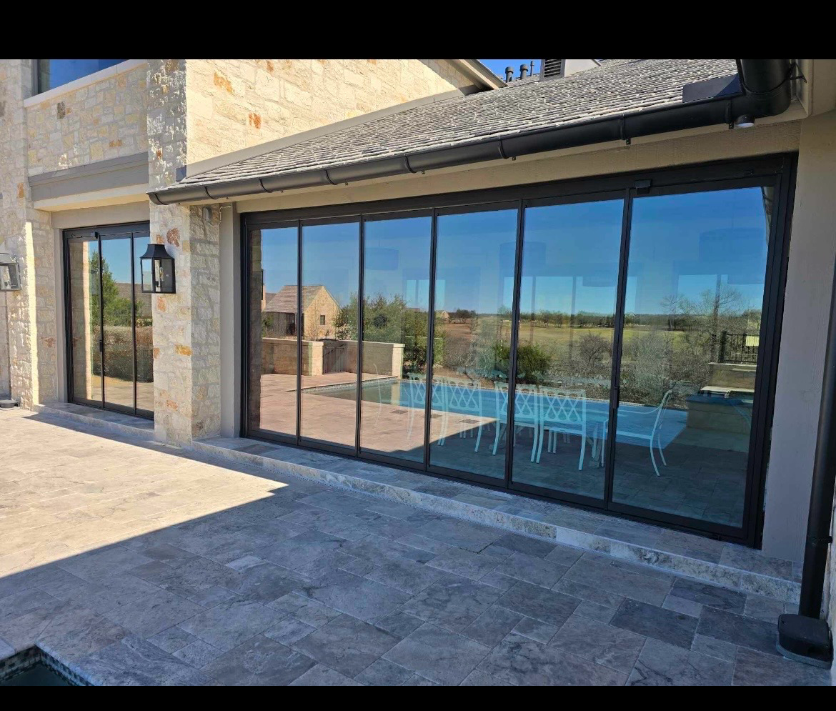 Black-frame multi-slide glass doors opening to a pool patio