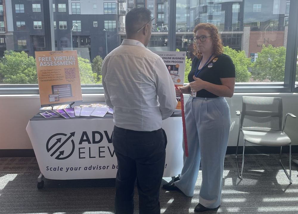 An Advisor Elevated team member talking with an advisor at a branded event table.