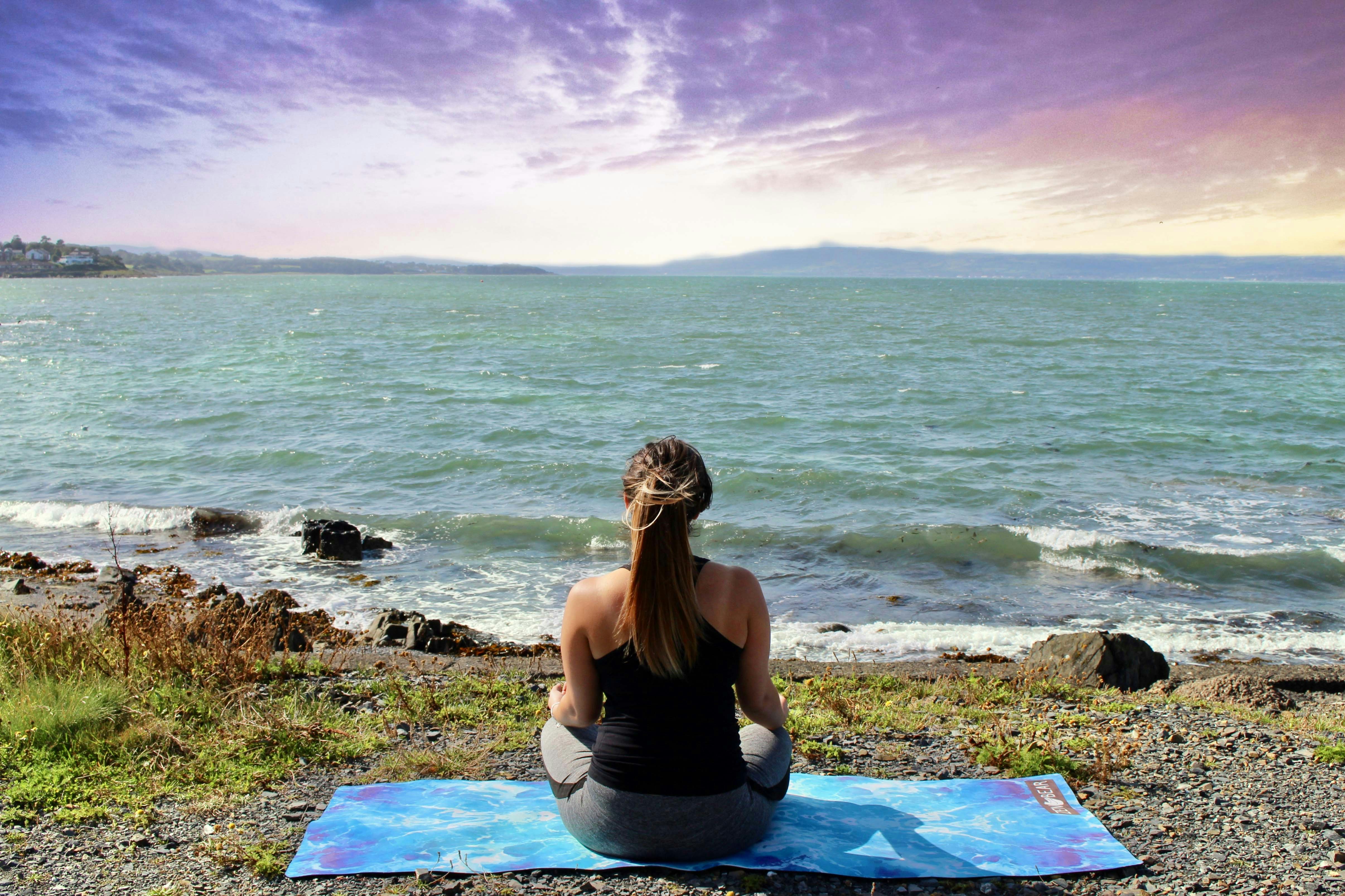 Woman meditating on the beach at sunset