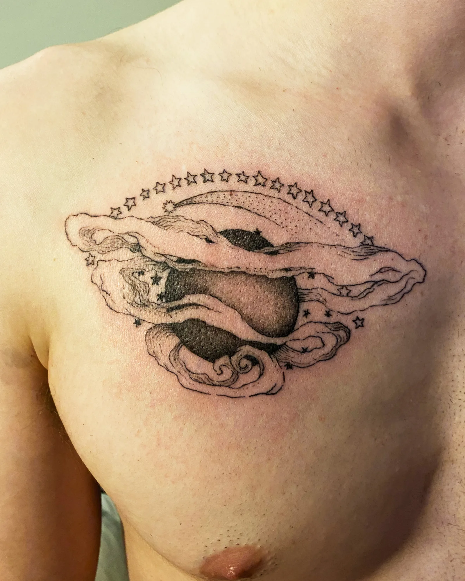 Fine line black and grey celestial clouds and stars chest tattoo by Meg at Studio AZ Tattoo Minneapolis