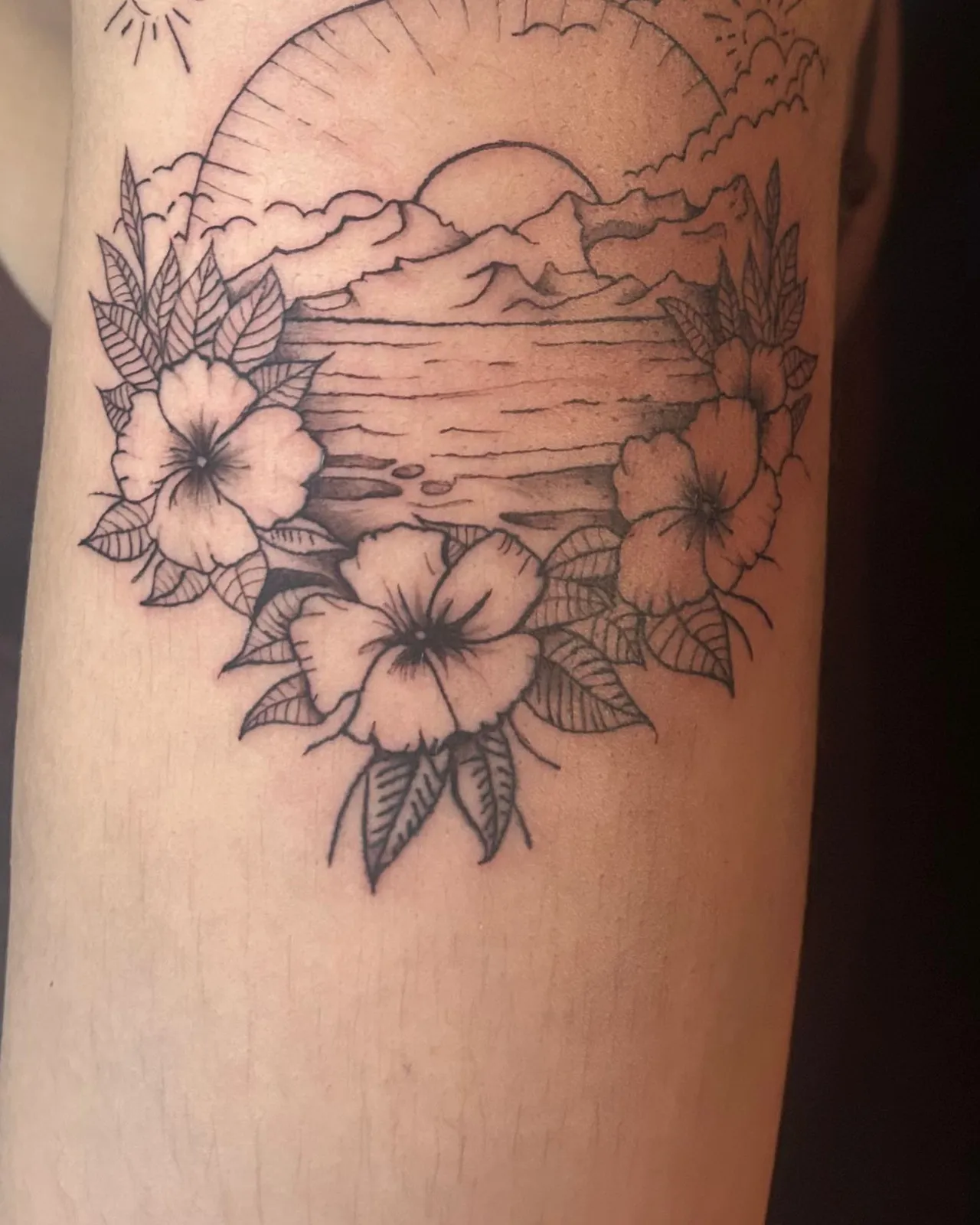 Fine line sunset over a lake with hibiscus flowers upper arm tattoo by Slick at Studio AZ Tattoo Minneapolis